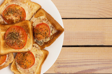 toast with cheese tomato basil oregano on a wooden background