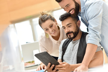 Team of cheerful designers working with tablet