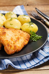 Fried pork chop in breadcrumbs, served with boiled potatoes and