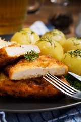 Fried pork chop in breadcrumbs, served with boiled potatoes and