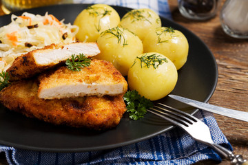 Fried pork chop in breadcrumbs, served with boiled potatoes and