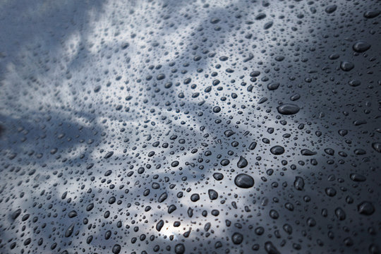 close up water drop, rain drop on a black surface car,selective focus