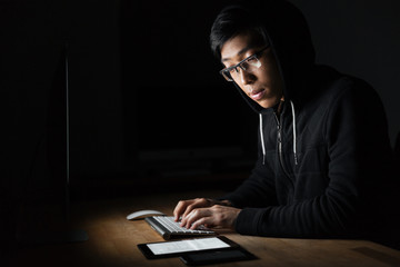 Hacker using laptop, tablet and smartphone in dark room