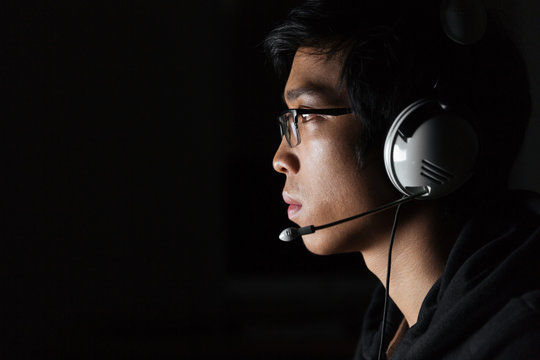 Serious young man using headset in dark room