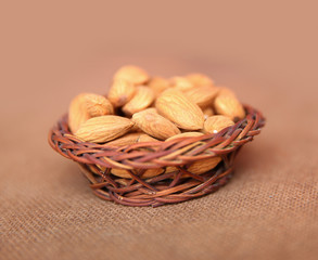 Almond on a wooden basket with against wooden background