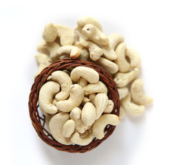Cashews on a wooden basket with against white background
