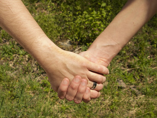 Two hands over green nature background. Love and friendship concept