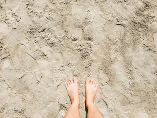 Selfie of barefoot on beach sand background, top view.