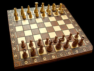 Wooden white and brown chessboard with aligned pieces, isolated in black, general view