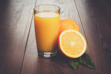 fresh orange and glass with juice on the brown wooden table