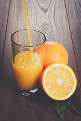 fresh orange juice pouring into glass on the brown wooden table