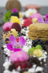 Presentation dessert, biscuit, fake caviar, molecular spheres, macarons, maltodextrin, chocolate, and edible flowers.