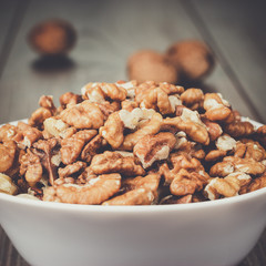 walnuts in the white bowl on brown wooden table