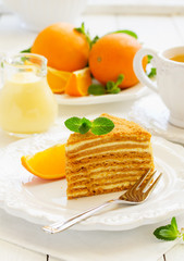 Homemade honey cake with orange cream on a white plate.