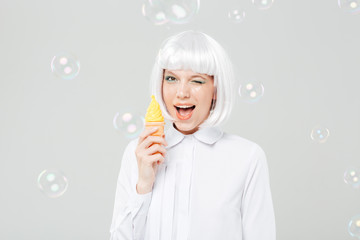 Cheerful playful young woman winking and holding fake ice cream