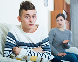 Adult woman lecturing unpleased teenager in home interior