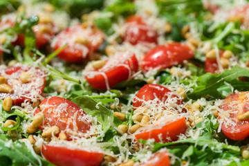 Salad with arugula, tomatoes, parmesan and pine nuts