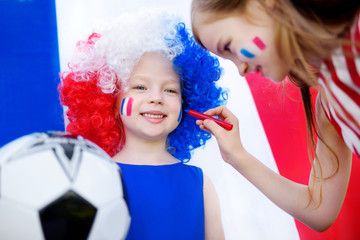 Two funny little sisters supporting and cheering their national football team