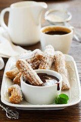 Churros with hot chocolate and powdered sugar.