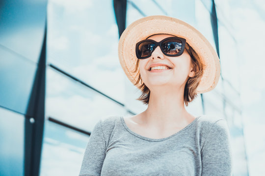 Smiling woman in sunglasses near glass building