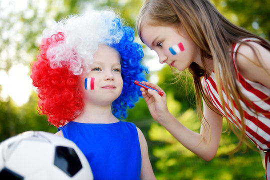 Two funny little sisters supporting and cheering their national football team