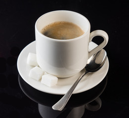 coffee cup, spoon, against a black background