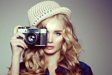 Young woman with camera. Blonde in a plaid shirt. Hipster fashio