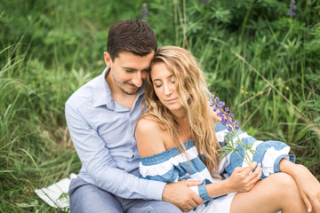 young couple man and woman sitting in an embrace on plaid outdoo