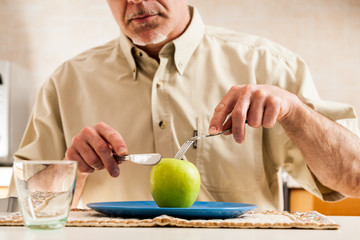 Fototapeta premium Obscured man slicing apple over blue plate