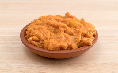 Portion of spicy chicken salad in a small bowl on a wood table.