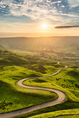 Kronkelende landweg die leidt naar Edale in het Engelse Peak District met prachtig gouden licht dat door de vallei schijnt.