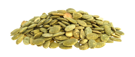 Organic dry roasted pumpkin seeds on a white background.