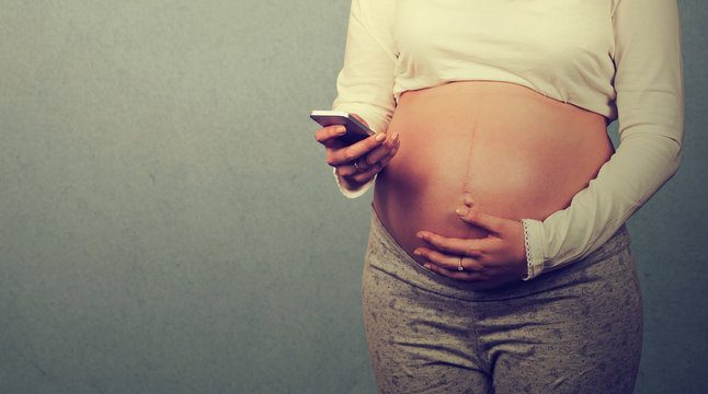 Cropped closeup image young pregnant woman texting on mobile phone