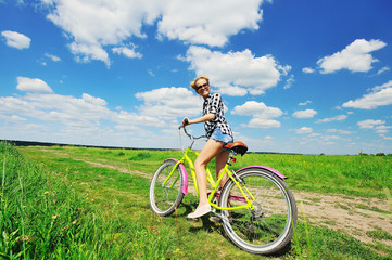 Obraz premium Beautiful girl riding bicycle outdoors across the green sunny field