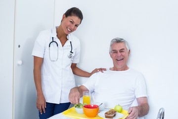 Portrait of senior man and female doctor smiling in hospital