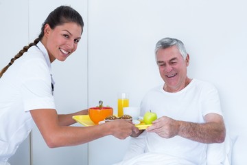 Female doctor serving breakfast to senior man