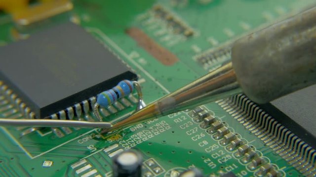 4K extreme close up view of resistance soldering technique on circuit board using iron tool
