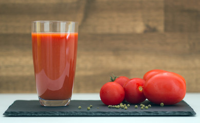 Glass of tomato juice on wooden table
