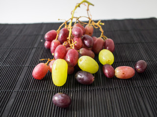 Red grapes on bamboo mat black.