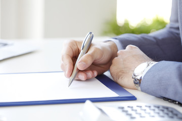 Signing the contract. Close-up image of a businessman's hands initialing some paperwork. 