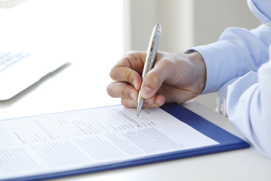 Signing the contract. Close-up image of a businessman's hands initialing some paperwork. 