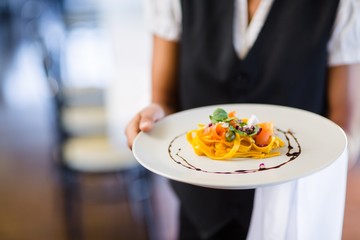 Mid section of waitress holding plate