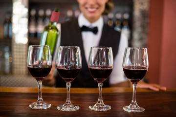 Four glasses of red wine ready to serve on bar counter