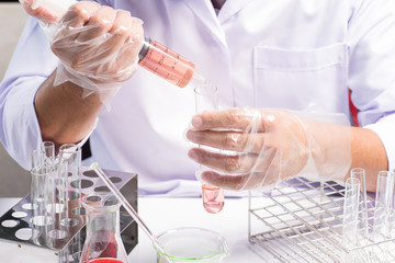 Conical flask in scientist hand with lab glassware background, L