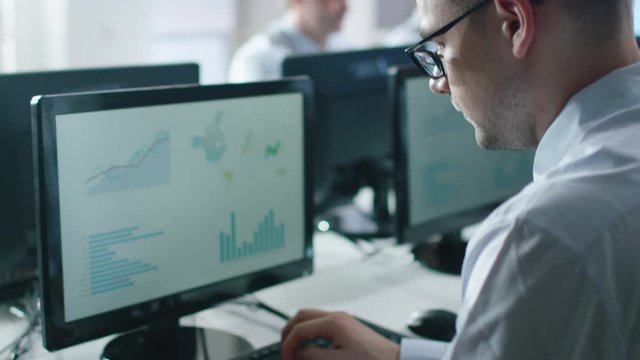 Team of Professionals Working at the Computers in Bright Office. Man Working with Charts. Shot on RED Cinema Camera in 4K (UHD).