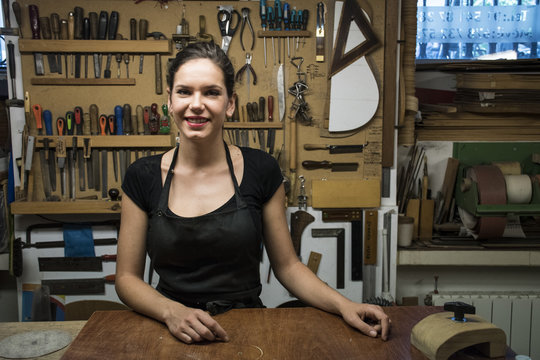 Portrait of smiling luthier in her workshop