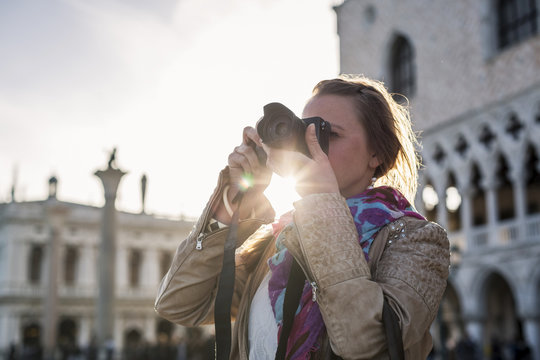 Italy, Venice, female Tourist taking pictures with camera, agsinst the sun