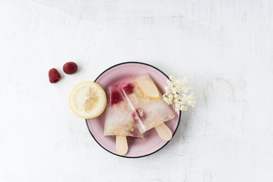 Homemade elderflower lemon raspberry ice lollies in bowl