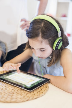 Girl wearing headphones using digital tablet