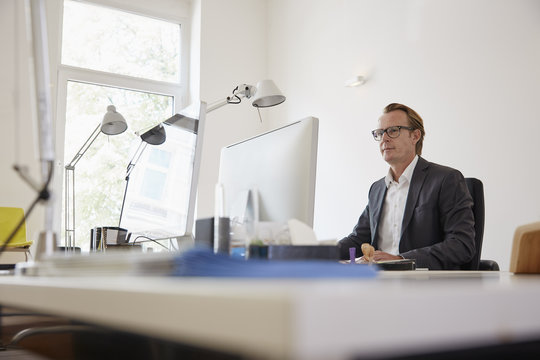 Businessman sitting at desk in an office working with computer